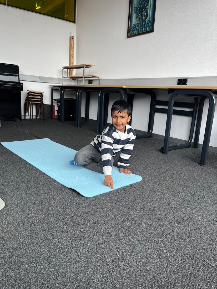 A child settling onto a yoga mat