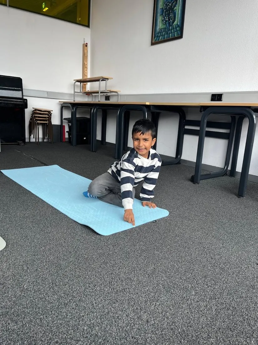 A child settling onto a yoga mat