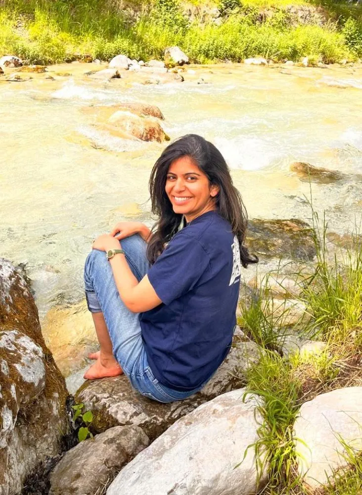 Surbhi Kakar sitting by a mountain stream